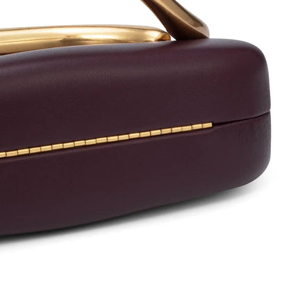 Close-up of a purple handbag with gold accents on a white background