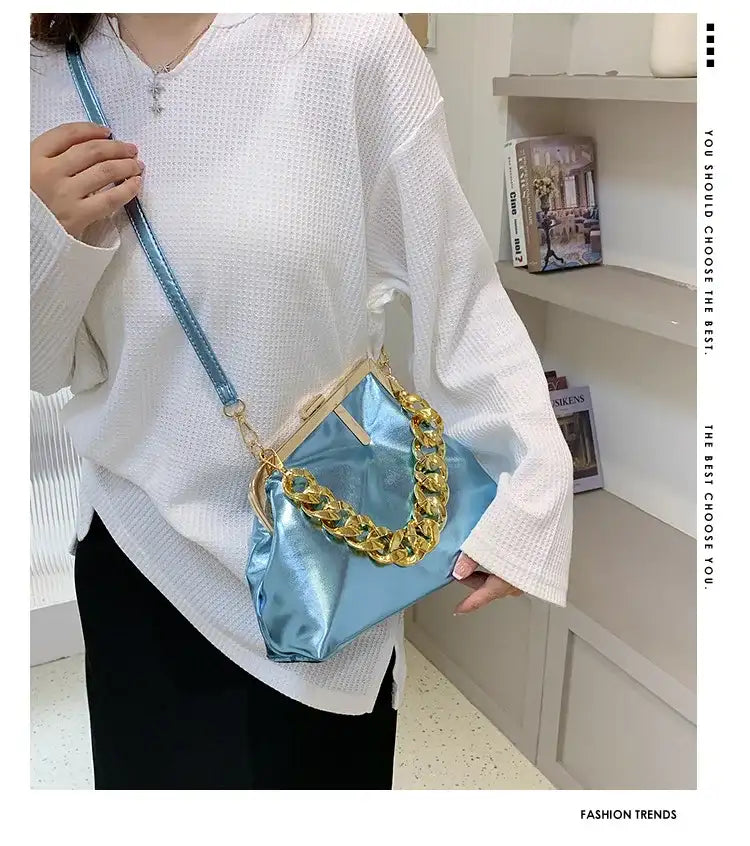 Person holding a Carauana UNIU Aurora Clutch with gold chain detail indoors