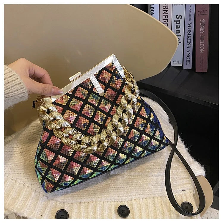 Multicolored patterned handbag with braided handle held by a hand on a textured surface.