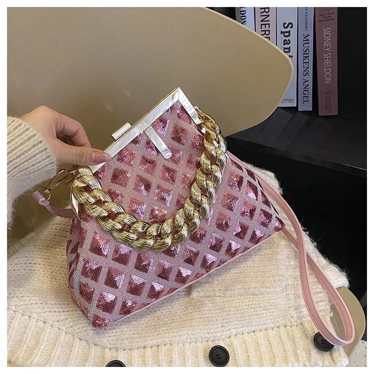 Pink and gold handbag held by a person wearing a beige sweater.