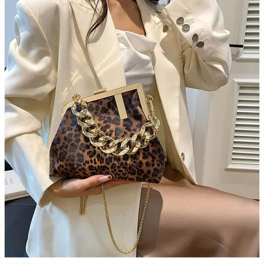 Person holding a Carauana UNIU Leopard Clutch with gold chain detail