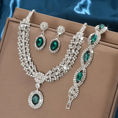 Jewelry set with necklace, earrings, and bracelet featuring green gemstones on a brown surface.