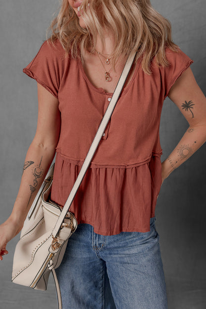 Person wearing a rust-colored top and blue jeans, holding a beige bag against a gray background