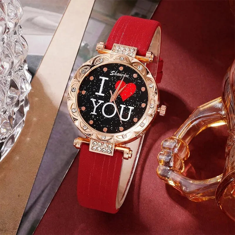 Wristwatch with red strap and 'I <3 YOU' display on a decorative surface