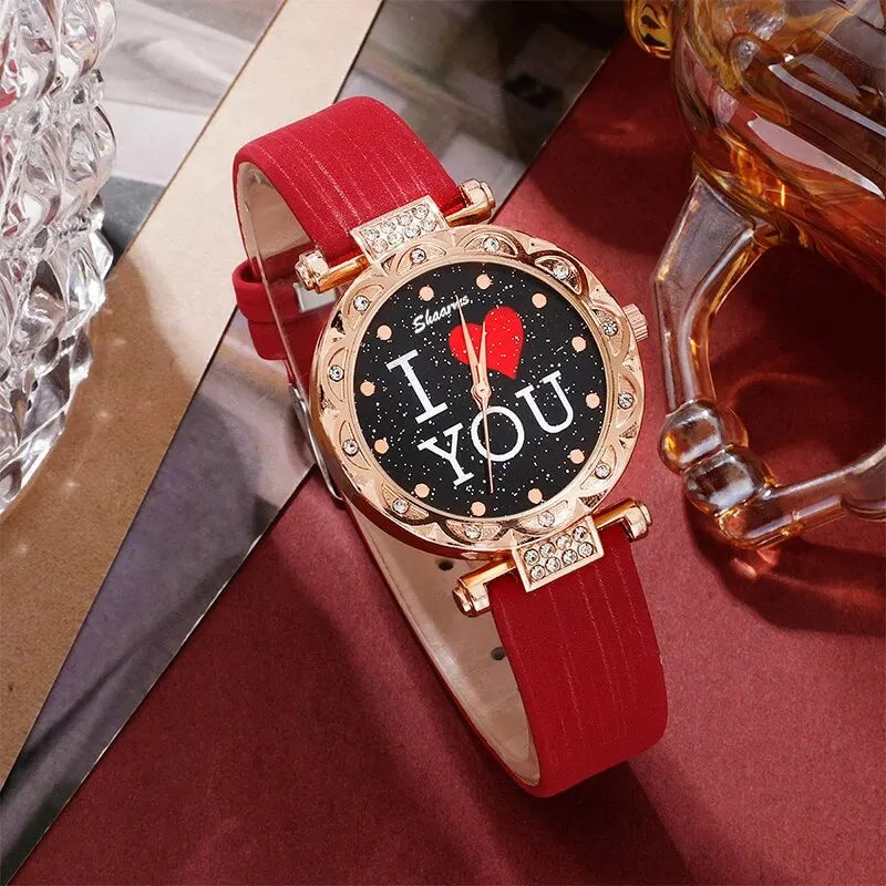 Wristwatch with red strap and 'I LOVE YOU' text on a reflective surface